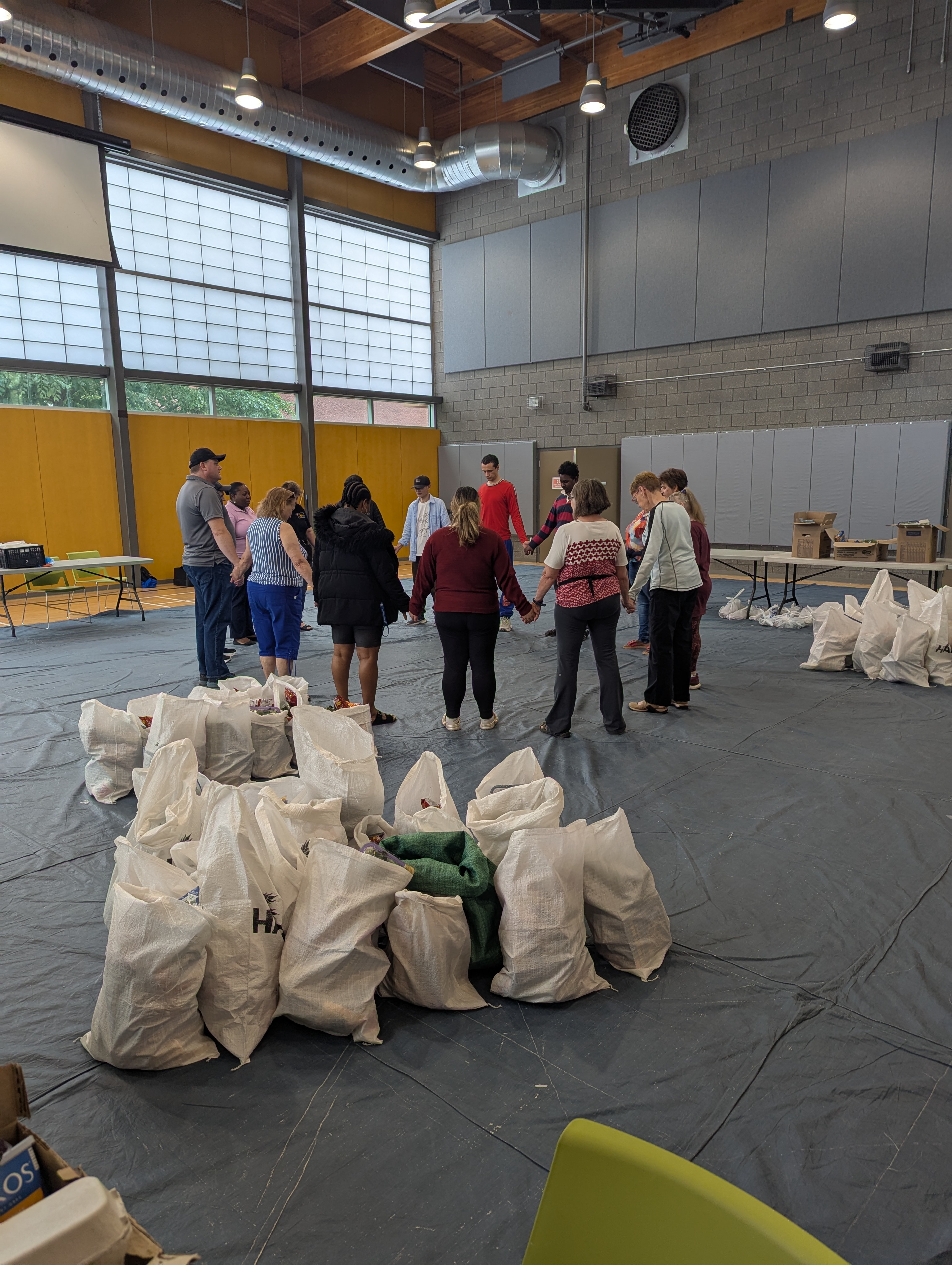 volunteers holding hands and praying after volunteering at the harvest food bank