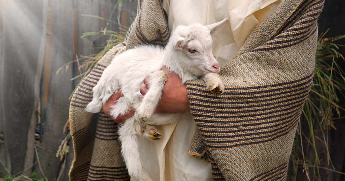 A robed person holding a lamb
