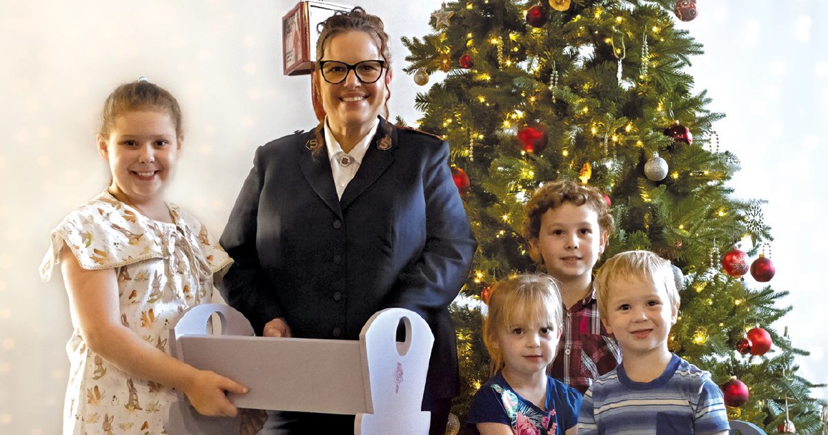 A Salvation Army officer and four children near a Christmas tree
