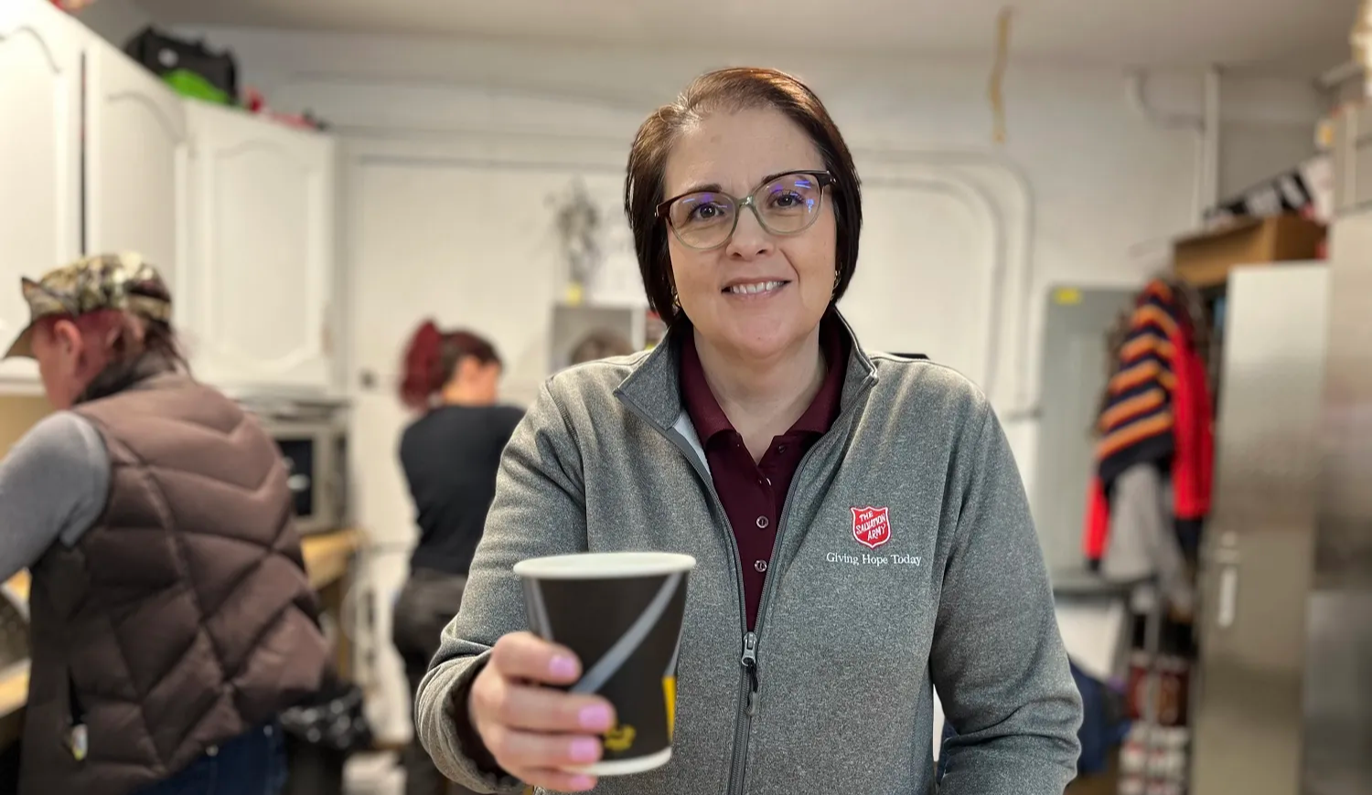 A volunteer holding a hot cup of coffee